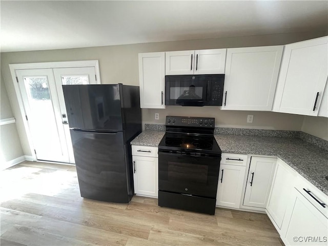 kitchen with light wood-type flooring, dark stone countertops, french doors, white cabinets, and black appliances