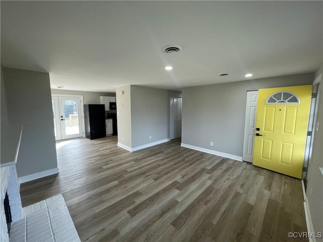 unfurnished living room featuring wood finished floors, visible vents, and baseboards