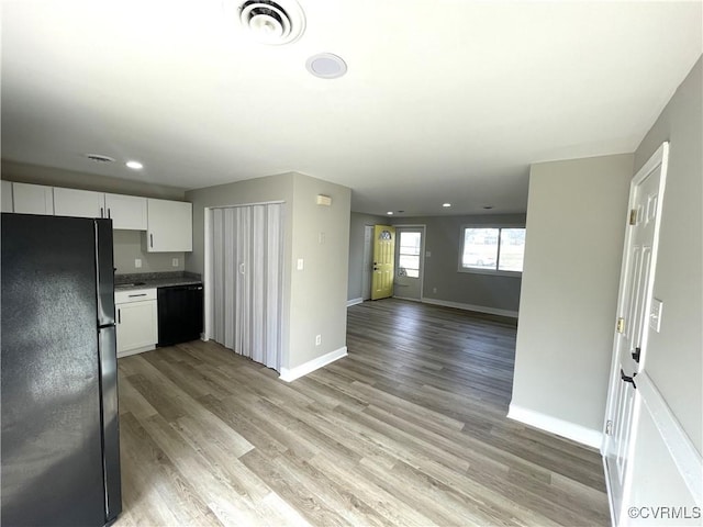 kitchen with visible vents, black appliances, light wood-style flooring, white cabinets, and baseboards