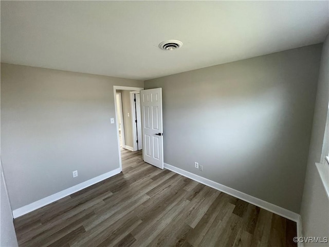 spare room with visible vents, baseboards, and dark wood-style flooring