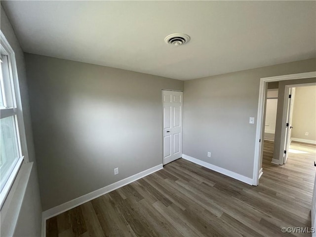 interior space featuring dark wood-type flooring, baseboards, and visible vents