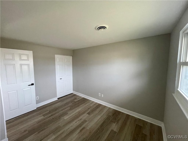 unfurnished bedroom featuring visible vents, baseboards, and dark wood-style flooring