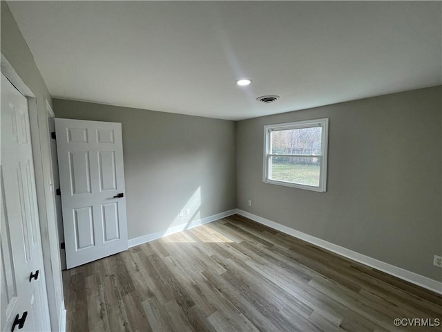 spare room featuring wood finished floors, baseboards, and visible vents