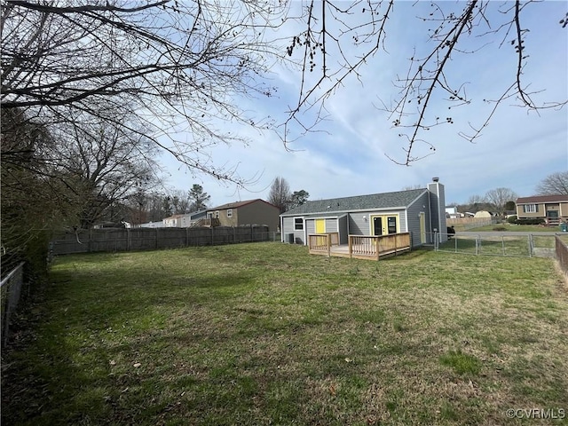 rear view of house featuring a deck, a fenced backyard, a lawn, and a chimney