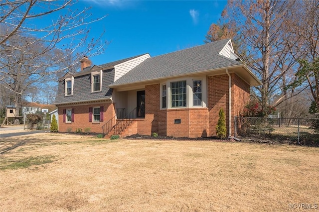 view of front of home featuring brick siding, roof with shingles, a front yard, and fence