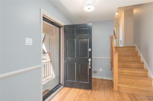 entryway with stairway, wood finished floors, visible vents, and baseboards