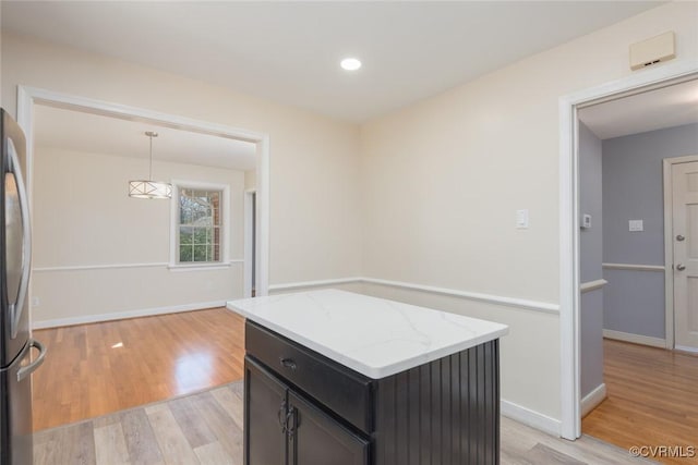 kitchen featuring light stone counters, baseboards, and light wood finished floors