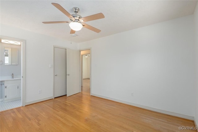 unfurnished bedroom with light wood-type flooring, ensuite bathroom, a sink, baseboards, and ceiling fan