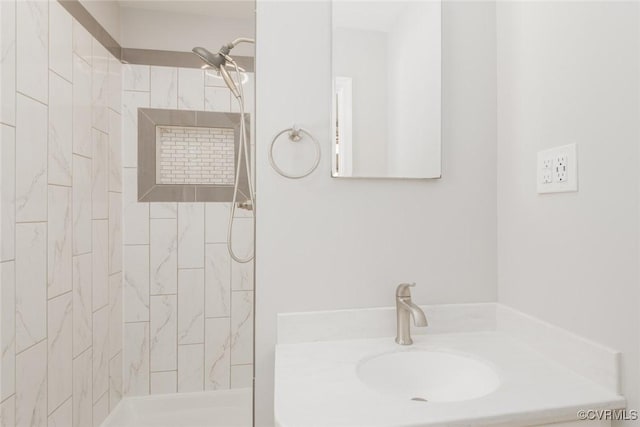 bathroom with a tile shower and vanity