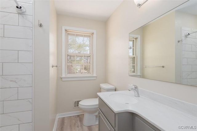 full bath featuring vanity, wood finished floors, visible vents, a tile shower, and toilet