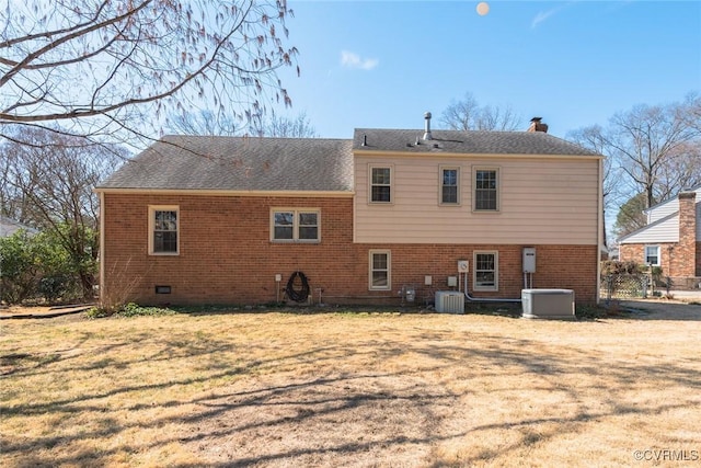 back of property featuring a shingled roof, central AC unit, brick siding, and a lawn