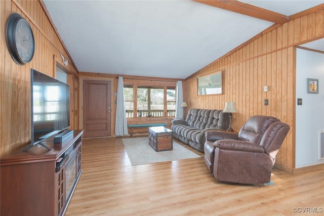 living room featuring a wealth of natural light, light wood-style floors, and vaulted ceiling with beams