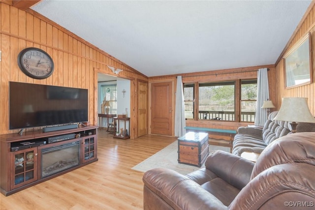 living area with a glass covered fireplace, wooden walls, lofted ceiling, and wood finished floors