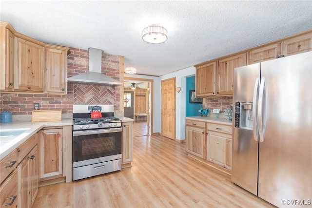 kitchen with light wood-style floors, appliances with stainless steel finishes, wall chimney exhaust hood, and light brown cabinets