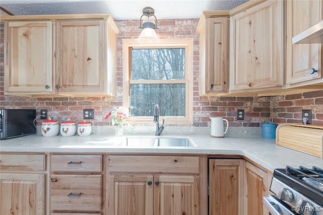 kitchen with a sink, stainless steel gas stove, and light brown cabinetry