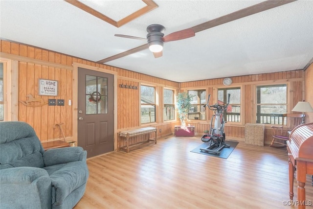 exercise area featuring wooden walls, a textured ceiling, ceiling fan, and wood finished floors