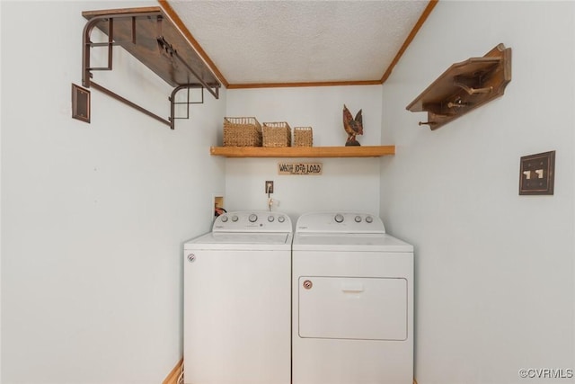 washroom featuring laundry area, washing machine and dryer, a textured ceiling, and crown molding