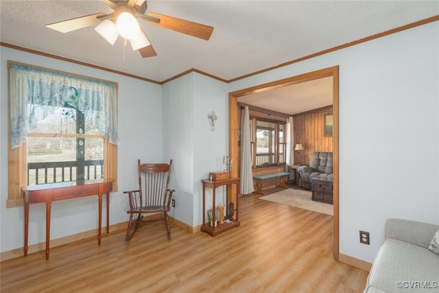 sitting room with baseboards, a textured ceiling, wood finished floors, and crown molding