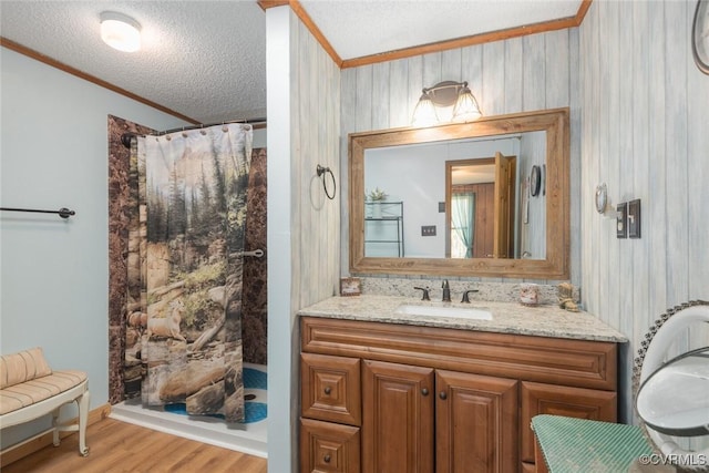 full bath with vanity, a shower with curtain, wood finished floors, ornamental molding, and a textured ceiling