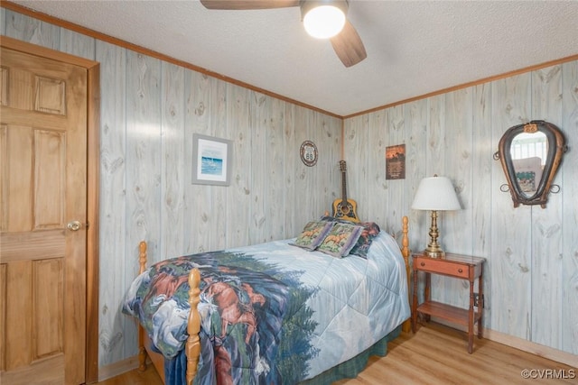 bedroom with a textured ceiling, crown molding, baseboards, and wood finished floors