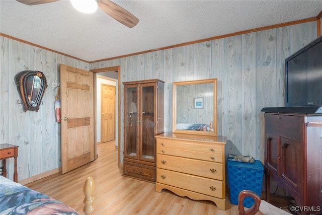 bedroom with ceiling fan, light wood-style flooring, a textured ceiling, and ornamental molding