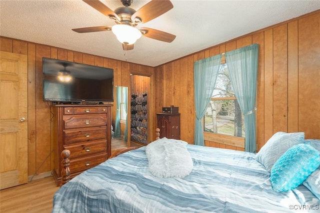 bedroom featuring wooden walls, light wood-type flooring, and ceiling fan