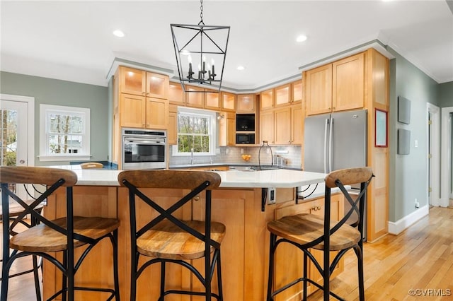 kitchen featuring light wood finished floors, glass insert cabinets, light countertops, decorative backsplash, and appliances with stainless steel finishes