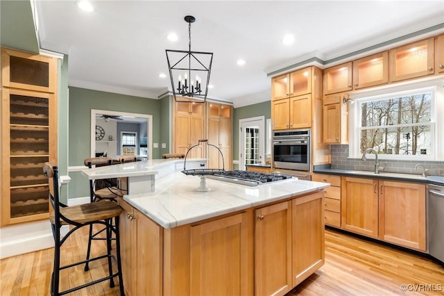 kitchen with a breakfast bar, an island with sink, a sink, decorative backsplash, and stainless steel appliances