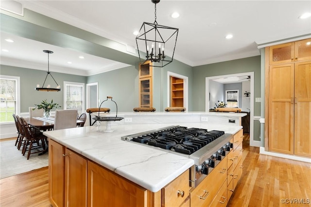 kitchen with stainless steel gas stovetop, light wood-style flooring, a center island, and ornamental molding