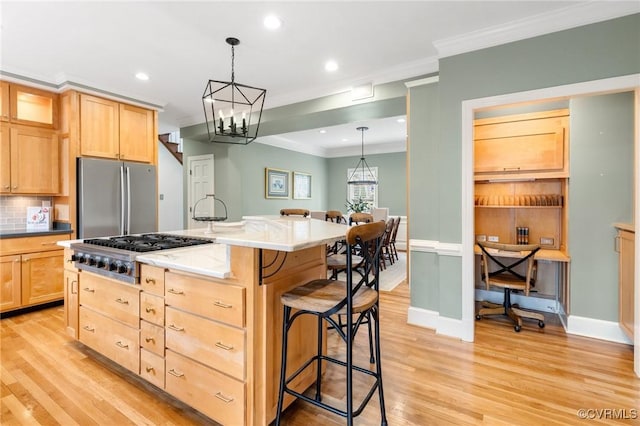 kitchen featuring light brown cabinets, appliances with stainless steel finishes, a breakfast bar area, and crown molding