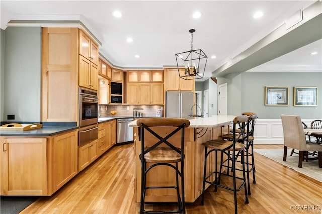 kitchen with a center island with sink, stainless steel appliances, light wood-style floors, crown molding, and a warming drawer