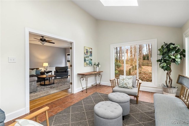 living area featuring baseboards, vaulted ceiling with skylight, and tile patterned flooring