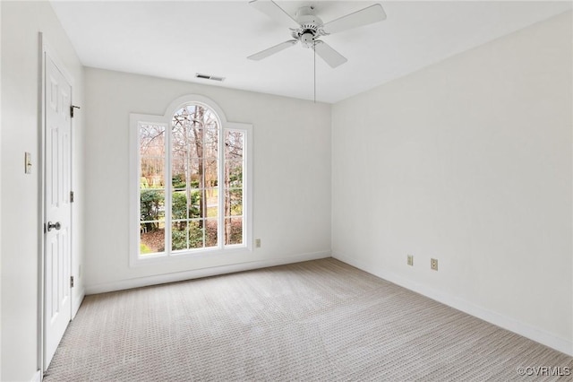 carpeted empty room featuring visible vents, baseboards, and ceiling fan