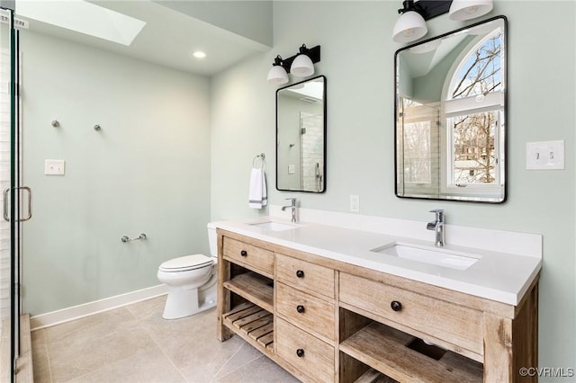 bathroom with a skylight, toilet, a stall shower, and a sink