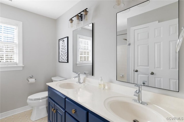 full bathroom with double vanity, toilet, baseboards, and a sink