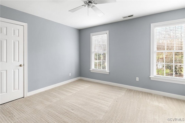 empty room with a ceiling fan, plenty of natural light, baseboards, and visible vents