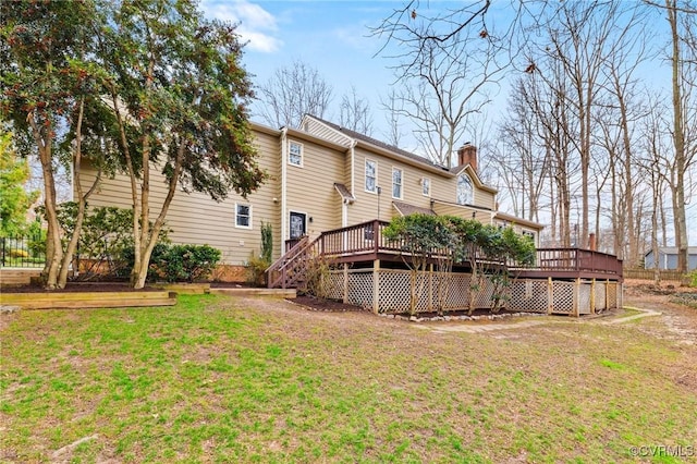 back of house with a lawn, a chimney, and a wooden deck