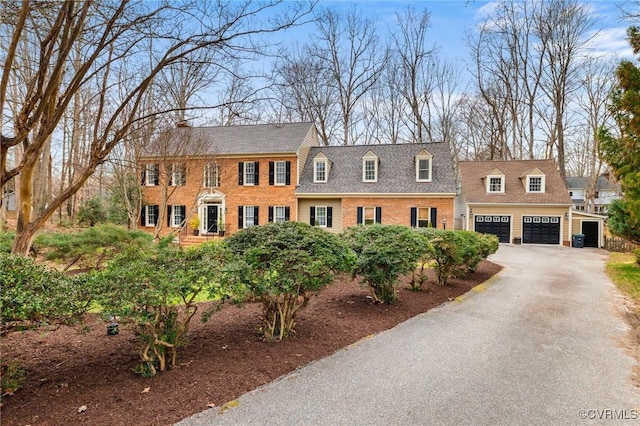 view of front of home featuring aphalt driveway, an attached garage, and brick siding