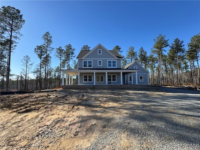 view of front of house featuring board and batten siding, covered porch, and gravel driveway