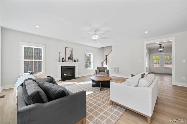 living room with visible vents, baseboards, stairway, light wood-type flooring, and recessed lighting