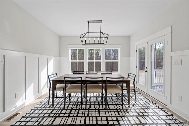 dining room featuring visible vents, wainscoting, a decorative wall, and an inviting chandelier