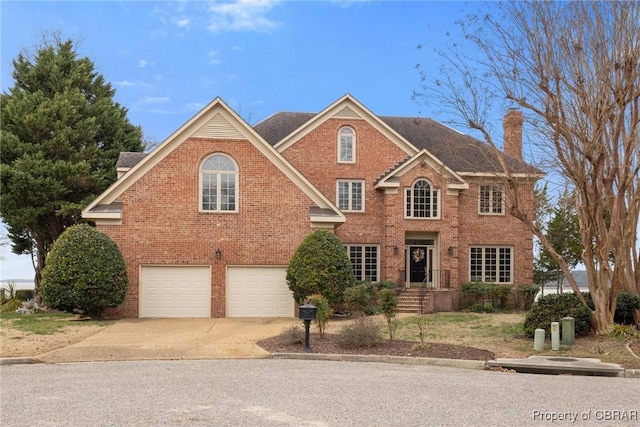 view of front of house with brick siding, driveway, a chimney, and a garage