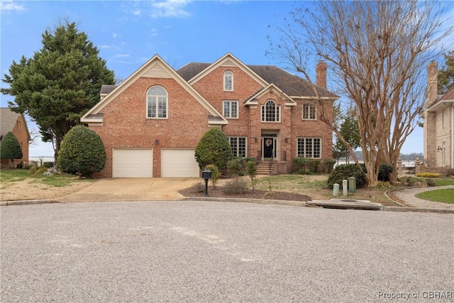 view of front facade featuring an attached garage, brick siding, driveway, and a chimney