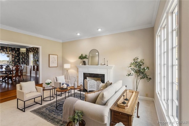 living area featuring a glass covered fireplace, a healthy amount of sunlight, and ornamental molding