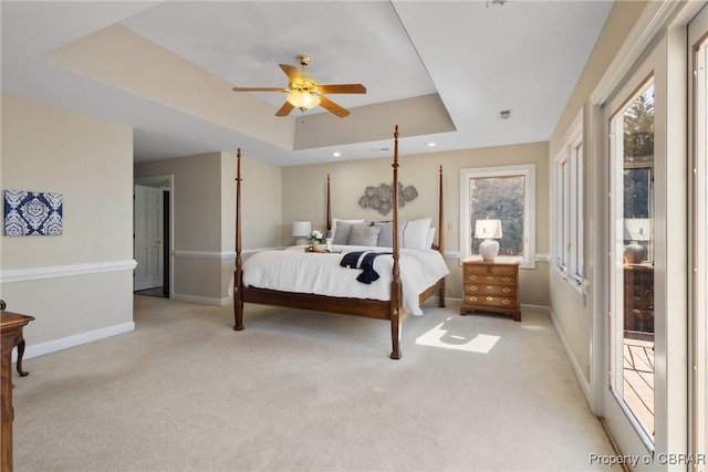 bedroom featuring a tray ceiling, visible vents, baseboards, and light carpet