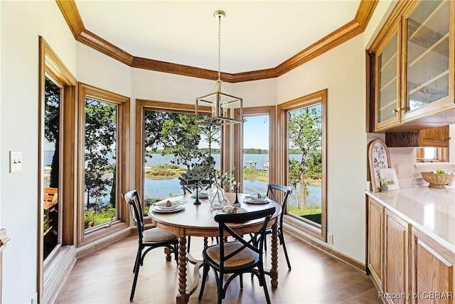 dining space with crown molding, baseboards, a water view, an inviting chandelier, and wood finished floors