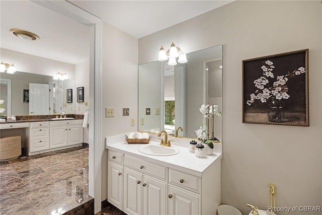 full bathroom with marble finish floor, two vanities, and a sink