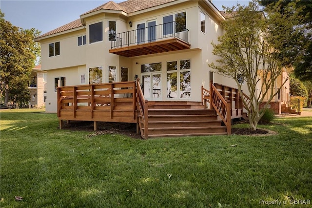 back of house with a balcony, stucco siding, and a yard