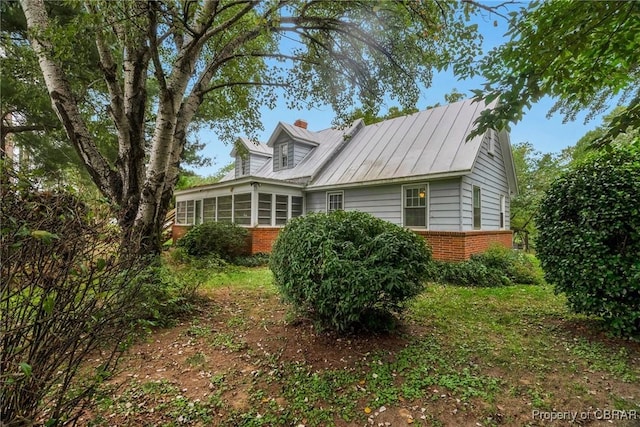 view of side of property with brick siding and a sunroom