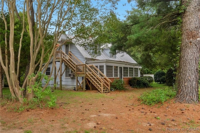 back of property featuring stairway, cooling unit, metal roof, and a sunroom